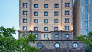 Un edificio de varios pisos con fachada simétrica, ventanas regularmente distribuidas y un elemento decorativo central.
