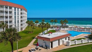 Un hotel con piscina, palmeras y vista al océano.