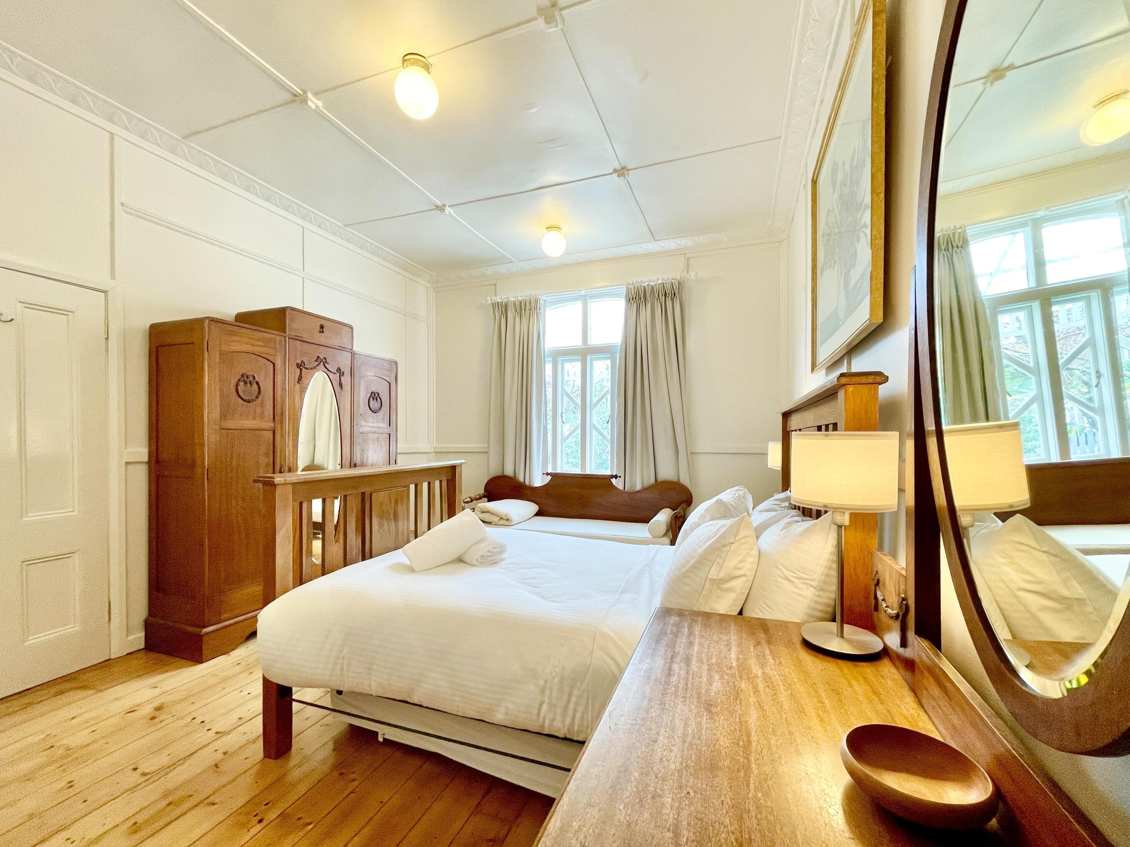Habitación de hotel con una cama y cómoda de madera, un espejo y una ventana con cortinas.