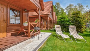 A wooden cabin with a porch, outdoor seating, and a well-maintained lawn. - 2 bedroom gorgeous home in Dabki, Bobolin (Dabki, Bobolin)