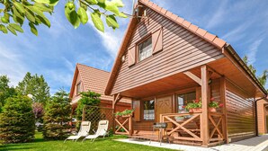 A wooden cabin with a sloped roof, a porch with outdoor seating, and a well-maintained lawn. - 2 bedroom gorgeous home in Dabki, Bobolin (Dabki, Bobolin)
