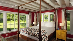 A four-poster bed with a patterned bedspread, a wooden nightstand with a lamp, and large windows with curtains. - Brisbane House: Restored Historic Stone House in the Country (Arena)