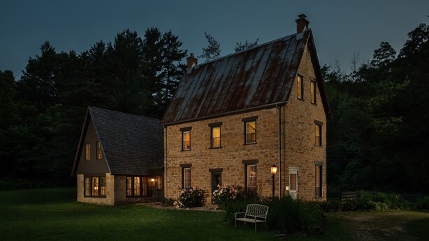 A rustic stone house with a steep gabled roof, multiple windows, and a well-maintained lawn. - Brisbane House: Restored Historic Stone House in the Country (Arena)