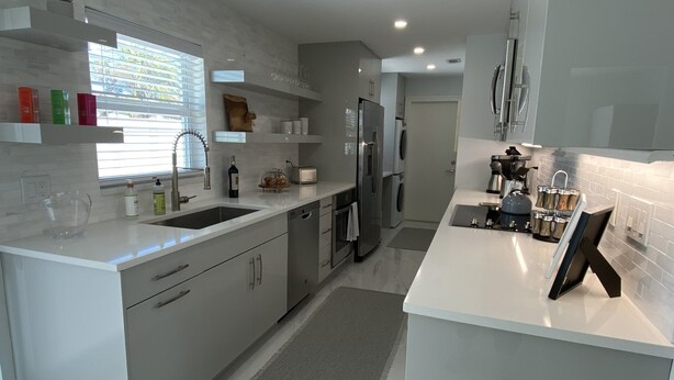 A modern kitchen with white cabinetry, stainless steel appliances, and a large window providing natural light. - Casa del Mare - Beautiful Naples Pool Home (Naples)