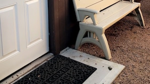 A white door with a keypad lock, a bench, and a window on a brown building. - Guesthouse studio Generac backup powered w washer&dryer. Fully equipped. (Spring)