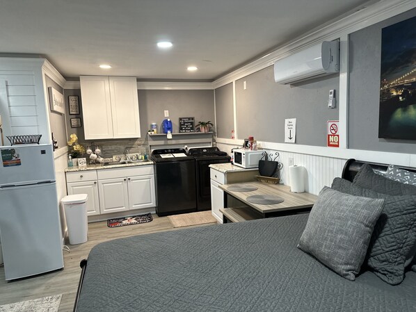 A compact kitchen with white cabinets, a black dishwasher, and a microwave. There is a small dining area with a table and chairs.
