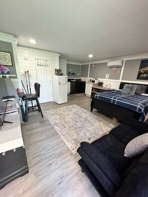 A compact, modern apartment with a kitchenette, a dining area, and a bedroom.