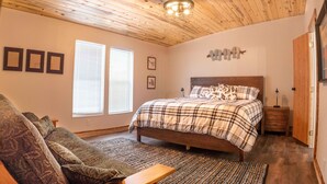 A bedroom with a bed, a sofa, a bench, and a wooden ceiling. - Flaming Gorge getaway/ Fly fishing paradise! (Dutch John)
