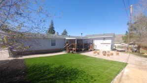 A residential property with a well-maintained lawn, a garage, and a deck area. - Flaming Gorge getaway/ Fly fishing paradise! (Dutch John)
