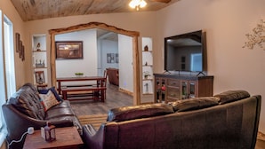 A cozy living room with a leather sofa, a wooden ceiling fan, and a flat-screen TV. - Flaming Gorge getaway/ Fly fishing paradise! (Dutch John)