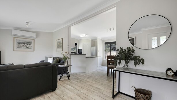 Un salon moderne avec un canapé foncé, une petite table ronde et un grand miroir.