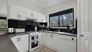 Une cuisine moderne avec des meubles blancs, un crédence en carreaux noirs, une grande fenêtre et un lave-vaisselle.