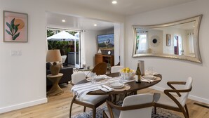 Un coin repas avec une table ronde dressée pour quatre personnes, un grand miroir et une vue sur l’extérieur.