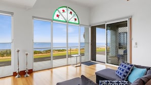 Une pièce spacieuse dotée d’une grande porte-fenêtre coulissante donnant sur un balcon, d’un canapé moderne et d’un vitrail décoratif.