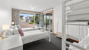 Une chambre moderne avec un lit, un bureau doté d’une lampe et une vue sur l’extérieur.