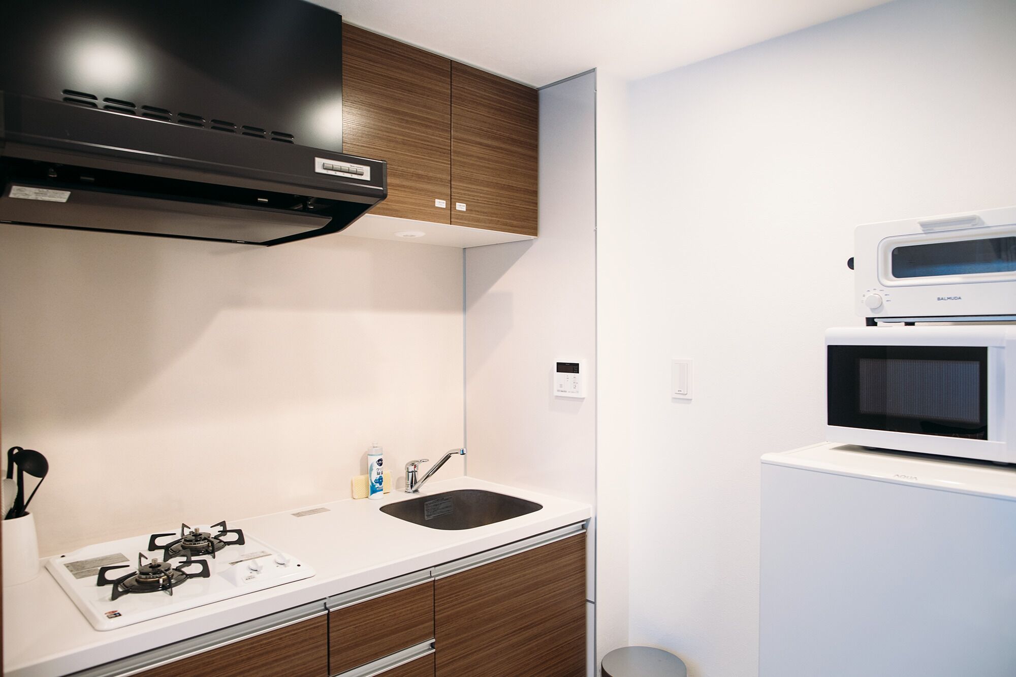 A compact kitchen with a gas stove, a microwave, and wooden cabinets.