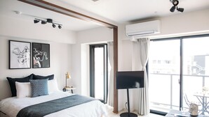 A modern hotel room with a bed, a flat-screen TV, an air conditioning unit, and a large window with a view. -  Section L Residence Asakusa East  (Tokyo)