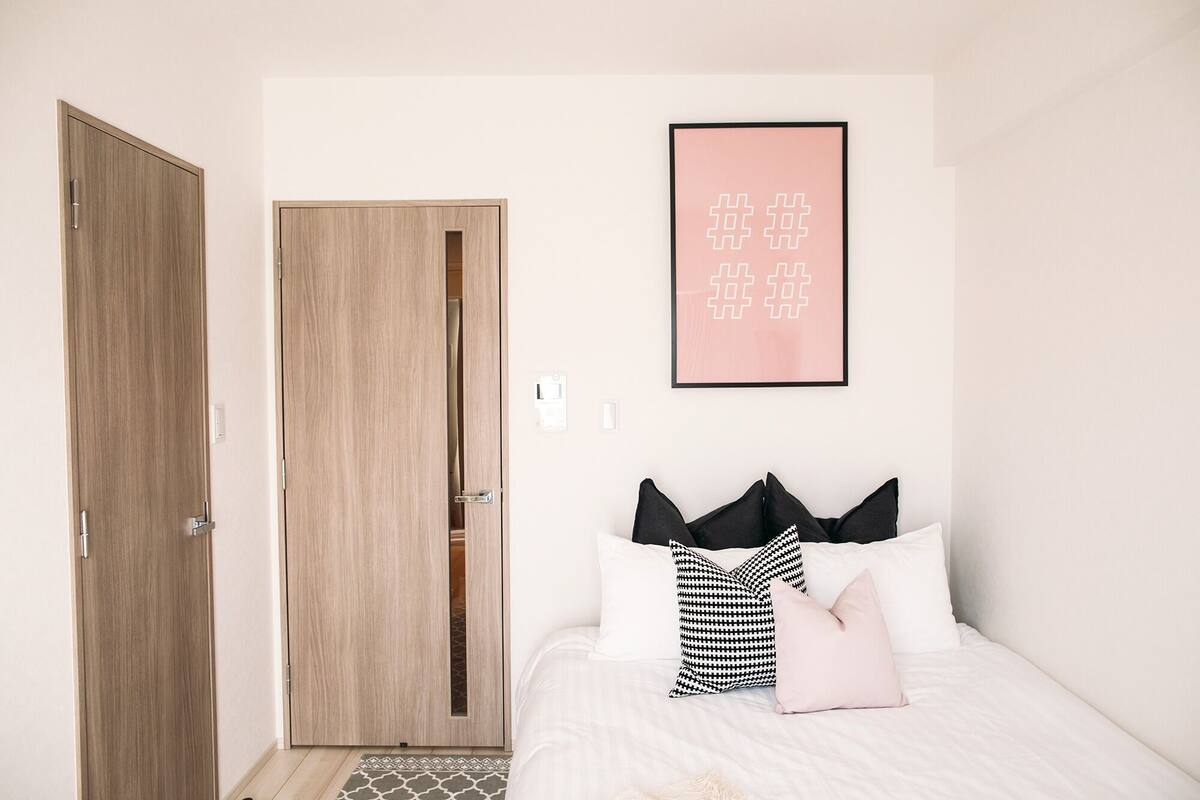 A bedroom with a bed, a framed picture on the wall, and two wooden doors.