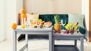 A dining table with fruit and glasses, a green sofa in the background, and a modern light fixture. -  Section L Residence Asakusa East  (Tokyo)