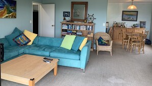 Uma sala de estar com um sofá verde-água, uma mesa de centro de madeira e uma estante repleta de livros.