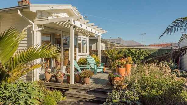 A house with a covered porch, potted plants, and a green chair.