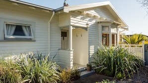 A house with a covered porch, a small front door, and a window with blinds.