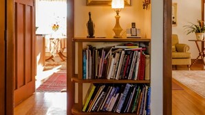 A hallway with a wooden bookshelf, a lamp, and a framed artwork on the wall.