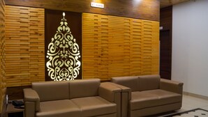 A lobby with a brown leather sofa, a decorative wall panel, and a sign indicating the location.