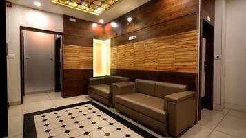 Un hall d’entrée moderne avec un sol à motifs hexagonaux, un canapé en cuir marron et des murs recouverts de panneaux en bois.