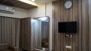 A modern bedroom with a flat-screen TV, a large mirror, a wardrobe, and an air conditioning unit.