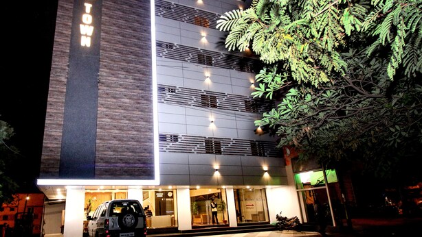 A hotel with a modern facade, a visible entrance, and a parked vehicle in front.