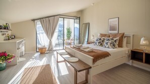 A modern bedroom with a large bed, a bedside table, a desk, and a window with curtains. - Payava Hotel by True Blue (Kas)