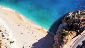 An aerial view of a beach with clear turquoise waters, a sandy shore, and rocky cliffs. - Payava Hotel by True Blue (Kas)