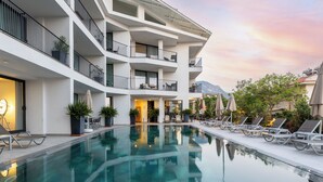 A modern hotel with a large indoor pool, multiple balconies, and outdoor seating areas. - Payava Hotel by True Blue (Kas)
