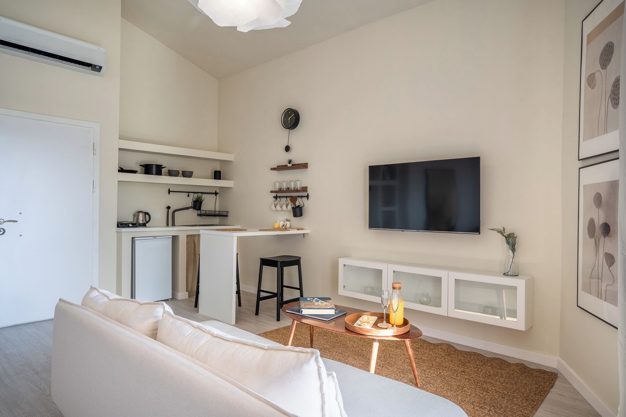 A modern living room with a sofa, a coffee table, a TV, and a kitchenette.