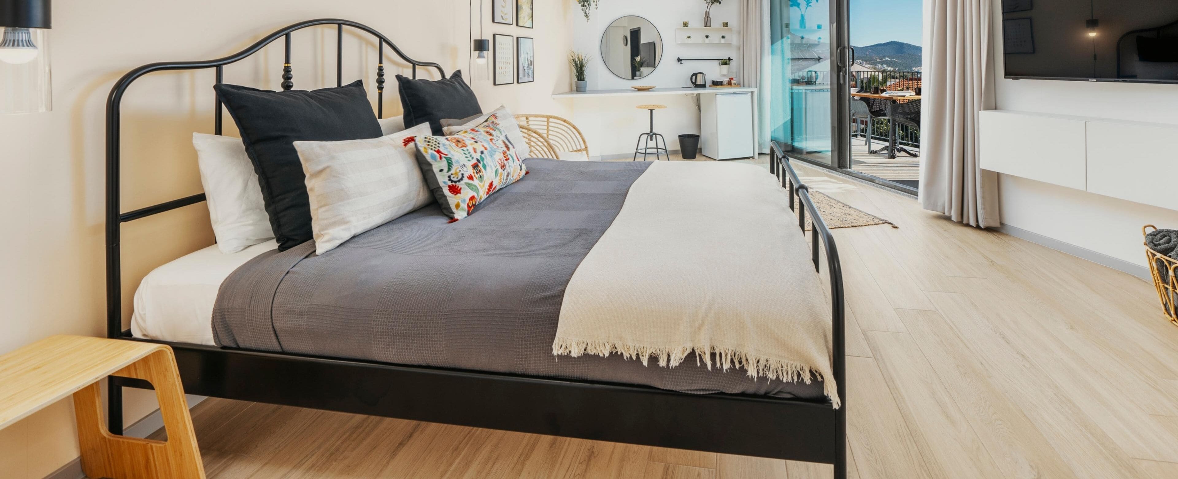 A modern bedroom with a bed, bedside table, and a view of a balcony.