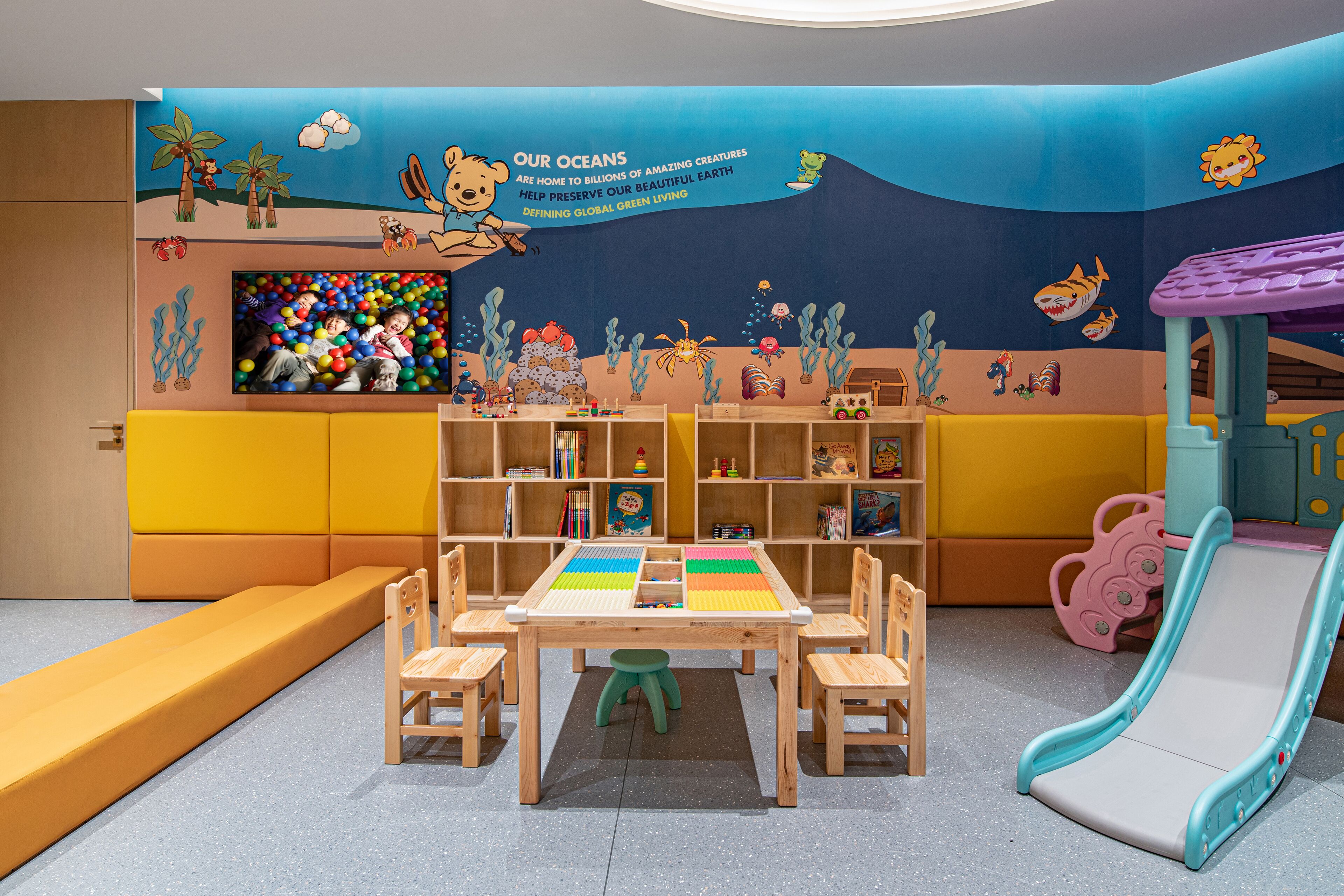 A children's play area with a slide, a play table, and colorful ocean-themed decorations.