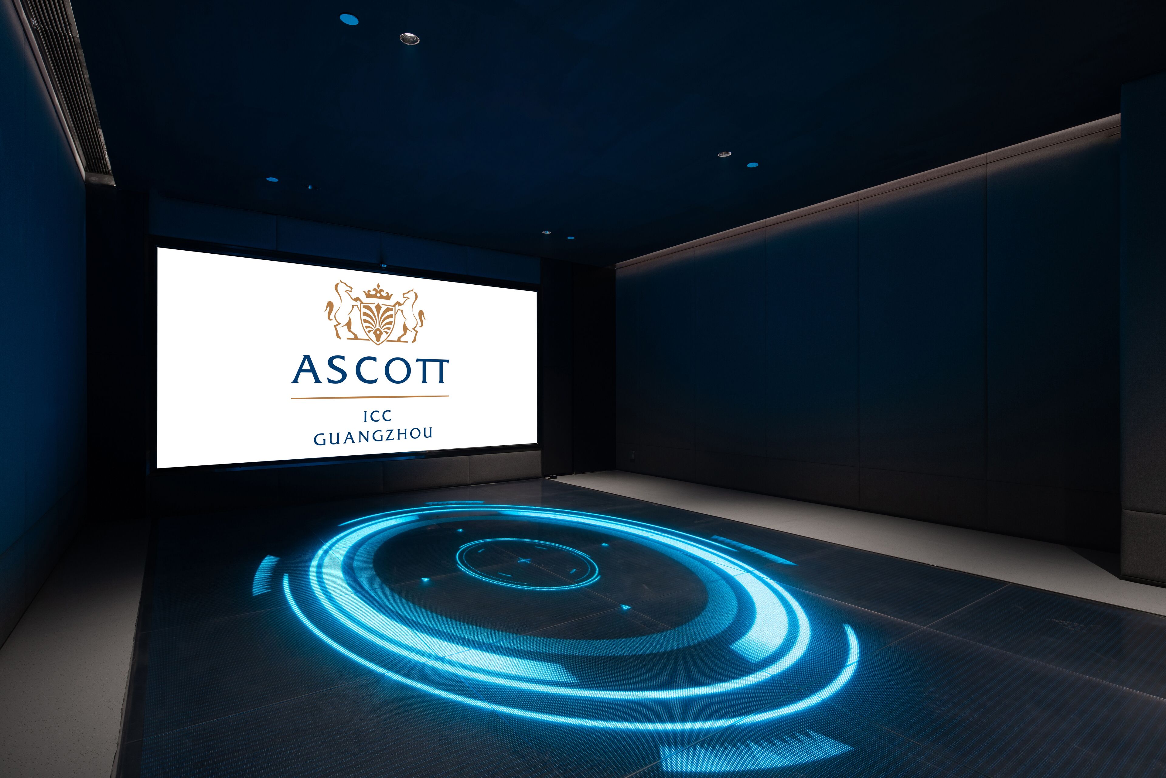 A modern, dimly lit room with a large screen displaying the ASCOTT logo and the location Guangzhou.