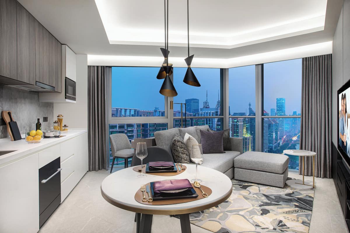 Una habitación de hotel moderna con comedor, sofá y televisión.