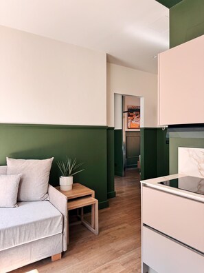 A compact room with a bed, a small table, a potted plant, and a kitchenette. - Asinelli apartment . (Bologna)