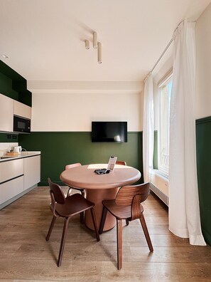 Een moderne keuken met een eethoek, een flatscreen televisie aan de muur en een raam met gordijnen.