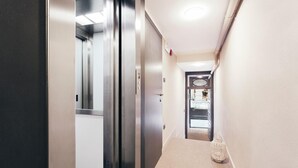 A narrow hallway with a carpeted floor, a door with a glass panel, and a small lantern on the right.