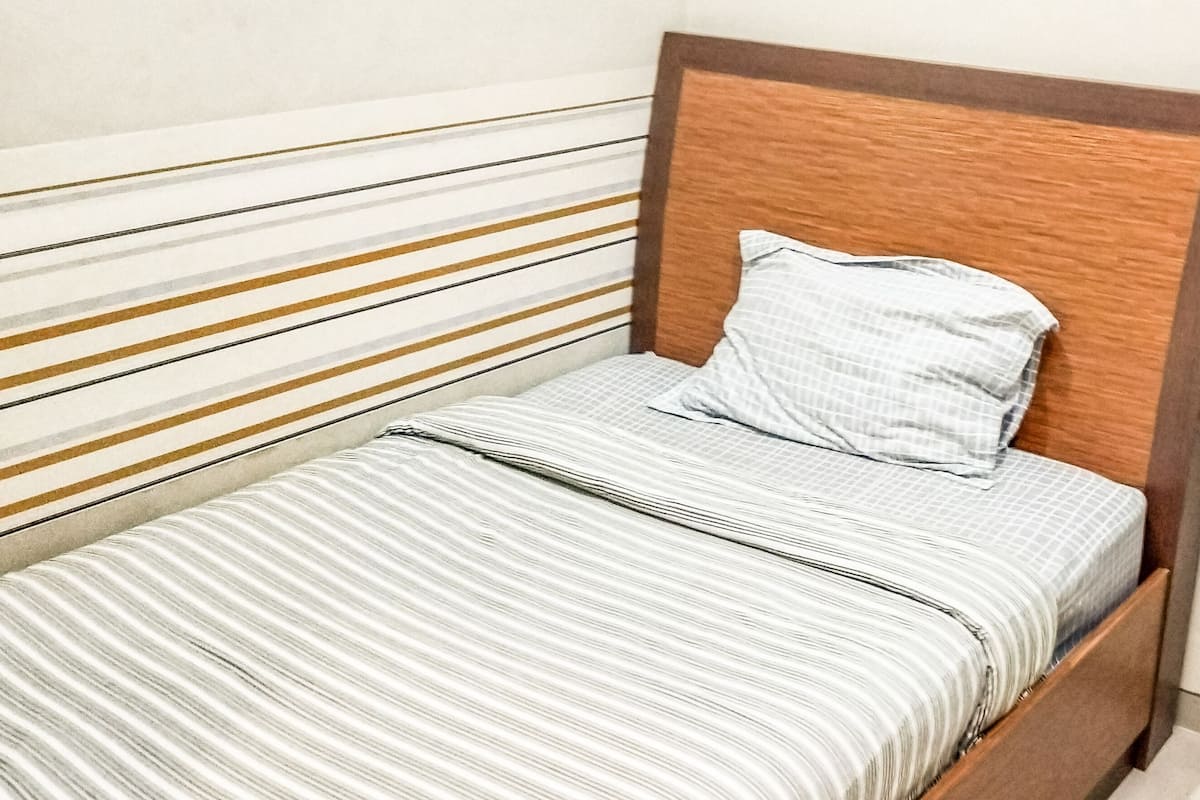 A single bed with a wooden headboard and a striped bedspread.