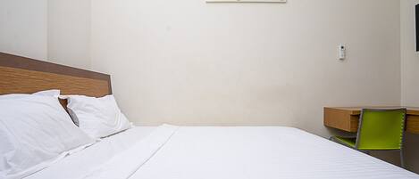 A neatly made bed with white linens, a wooden headboard, and a colorful painting on the wall.
