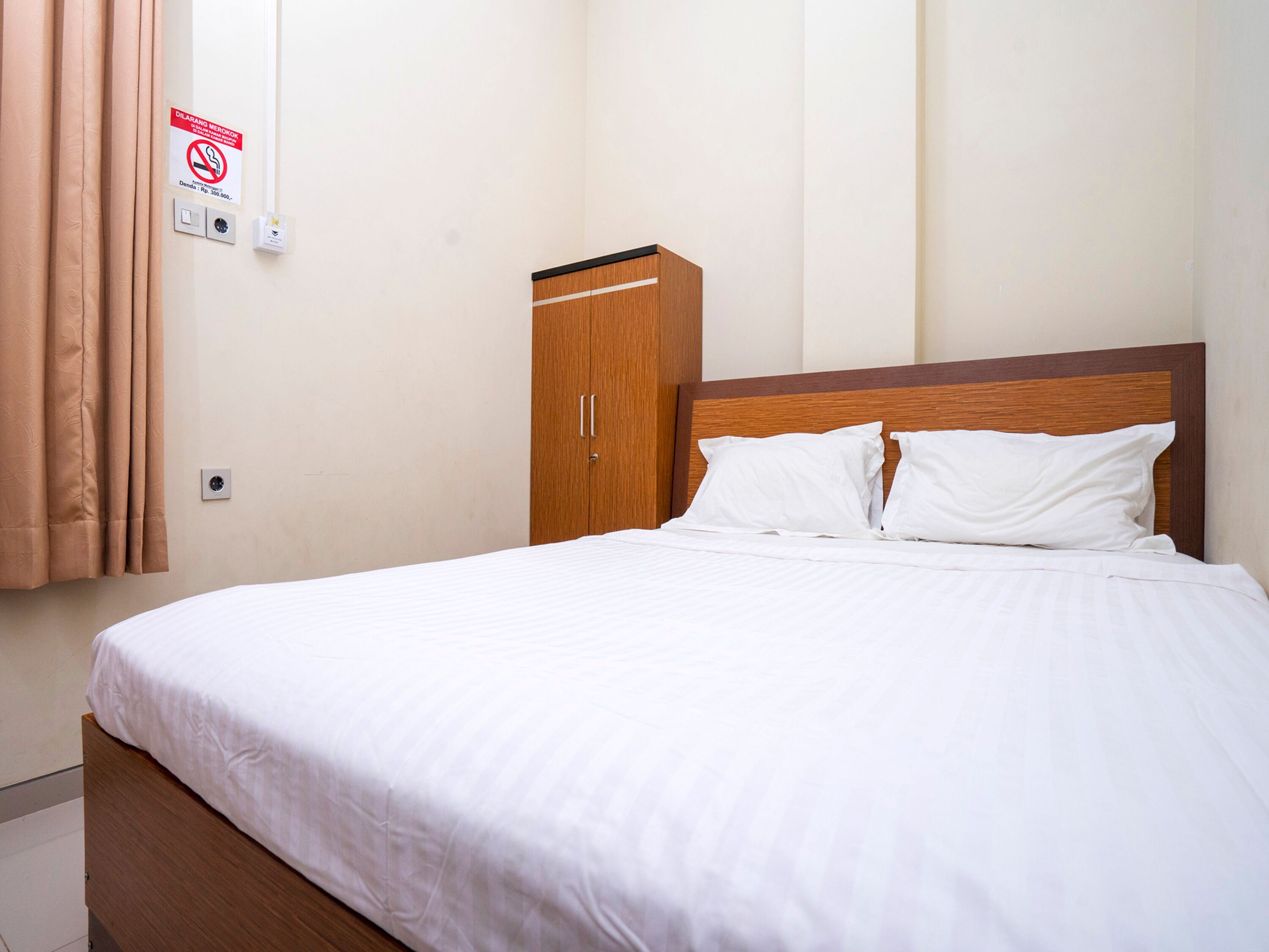 Een opgemaakt bed met witte lakens in een hotelkamer.