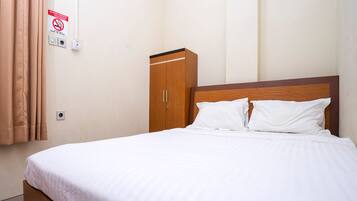Een opgemaakt bed met witte lakens in een hotelkamer.