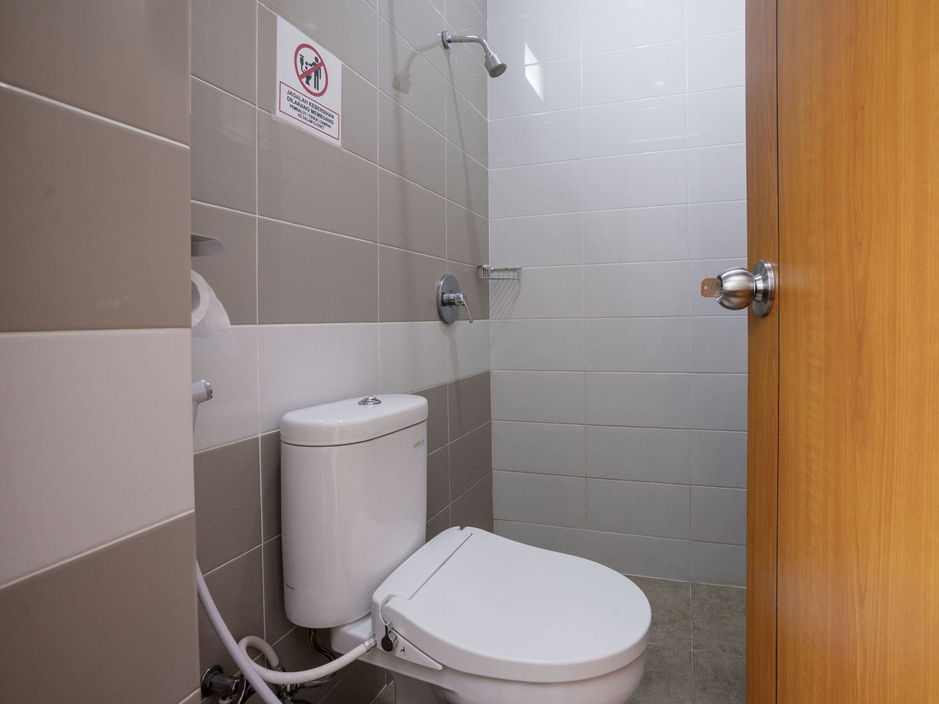 Un baño con inodoro, ducha y un cartel que prohíbe el uso de la ducha.
