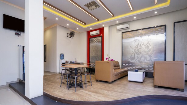 Eine moderne Hotelhalle mit Holzboden im Bogen, einer Rezeption, einer Couch und einem Couchtisch.