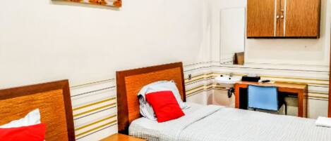 A hotel room with two beds, a wooden headboard, a bedside table, a mirror, a sink, and a cabinet.