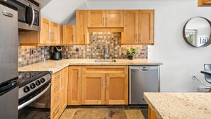 A kitchen with wooden cabinets, a microwave, stove, sink, and dishwasher.